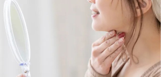 エラ張りやフェイスラインのたるみを気にして鏡を見る女性