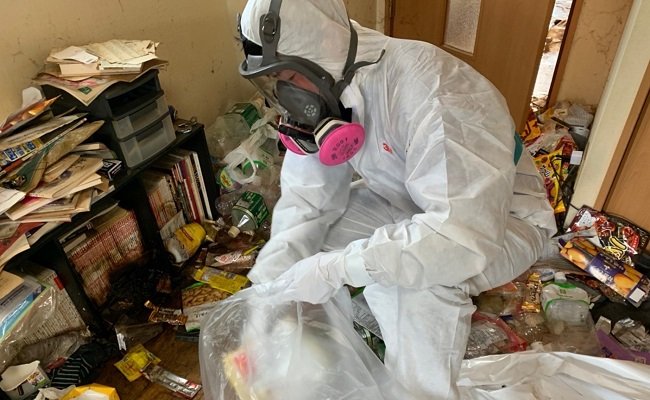 孤独死現場などで防護服と防毒マスクを着用し、ゴミの片付けや消臭作業を行う特殊清掃員