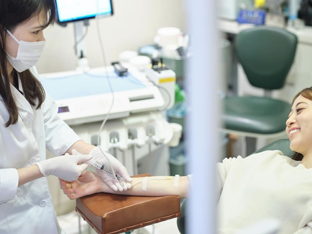 歯科の無痛治療（静脈内鎮静法）で点滴を受けながらリラックスして施術を受ける女性