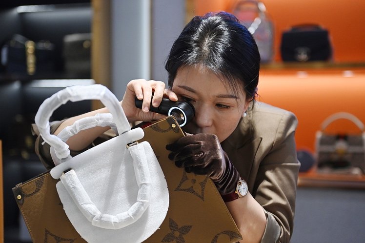 熟練の鑑定士がルーペを使用してブランドバッグの真贋判定と細かい傷を確認する高価買取の査定現場