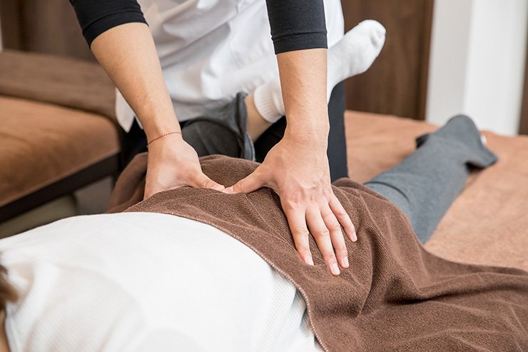 整体院で腰痛や骨盤矯正の施術（マッサージ・指圧）を行う男性整体師の手元